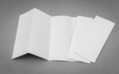 Four - fold white template paper on gray background .