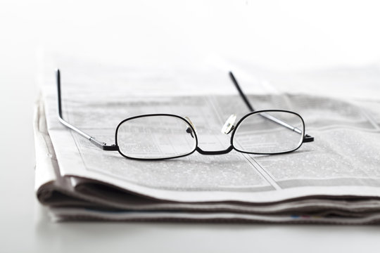 
Newspapers with eyeglasses on table
