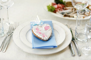 Gingerbread in form of heart lies on blue napkin on white dinner