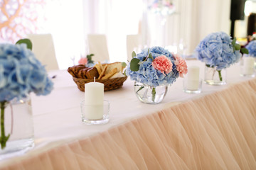 Bouquet of pinks and blue hydrangeas in little glass bowl stands