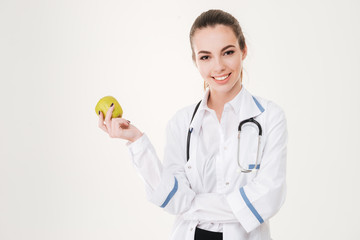 Happy young woman doctor smiling and holding an apple