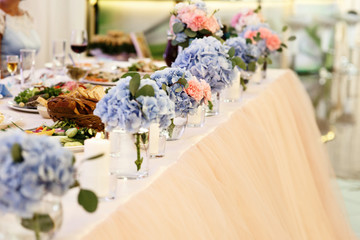 Tender bouquets of blue hydrangeas stand in glasses on dinner ta