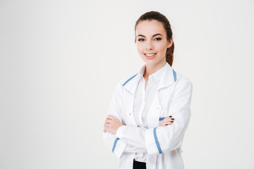 Happy beautiful young woman doctor standing with arms crossed