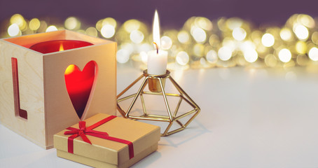 Candles and gift box with  red bow on golden bokeh background. Space for text