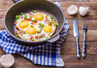 Fred eggs in pan with tomatoes and green fresh onion.