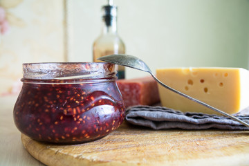Big piece of cheese, salami and jar with jam.