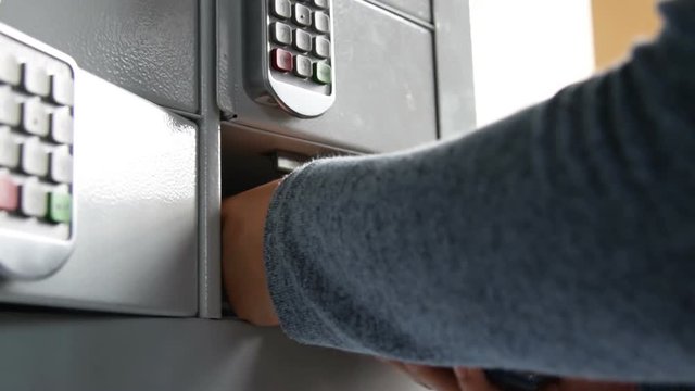 Close-up shot of a woman placing mobile phone into the locker with numeric code to charge it. Service at the railway station