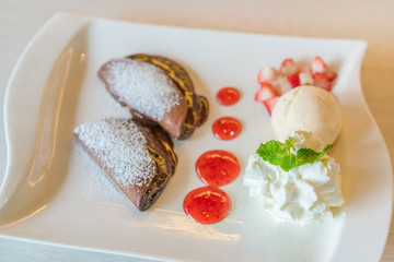 Pancake and fruit with ice cream on table .
