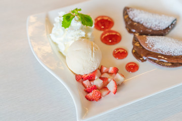 Pancake and fruit with ice cream on table .