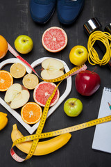 Diet plan, fruits and centimeter on a black background