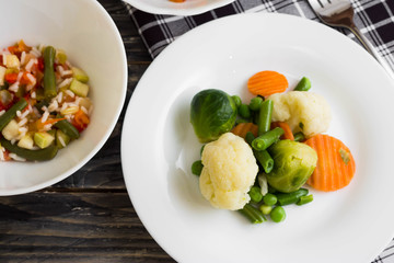 Vegetable salad in a white plate on a wooden background. Dietary dish.