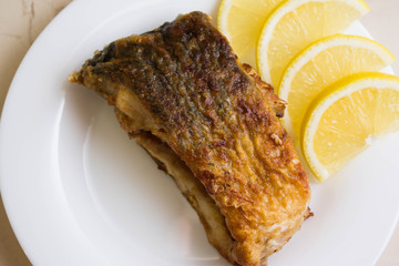 Fried carp with fried potatoes on a white plate