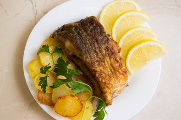 Fried carp with fried potatoes on a white plate