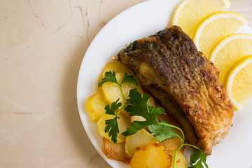 Fried carp with fried potatoes on a white plate