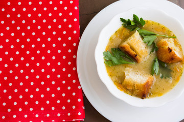 Pea soup with croutons in a white bowl on a marble table
