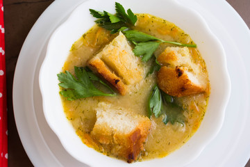 Pea soup with croutons in a white bowl on a marble table