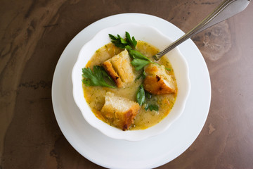 Pea soup with croutons in a white bowl on a marble table
