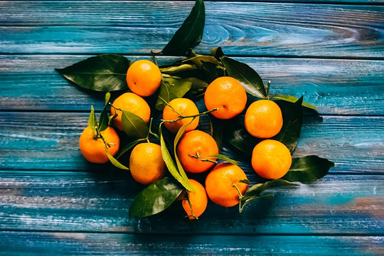 Tangerines with leaves on blue wooden table.