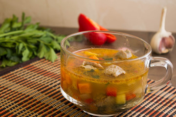 Vegetable soup with chicken giblets in a mug on the marble table