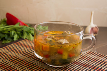 Vegetable soup with chicken giblets in a mug on the marble table