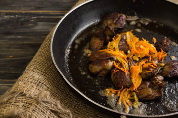 Fried chicken liver with vegetables in a frying pan