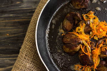 Fried chicken liver with vegetables in a frying pan