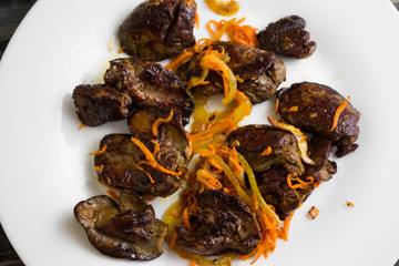 Fried chicken liver with vegetables on a white plate