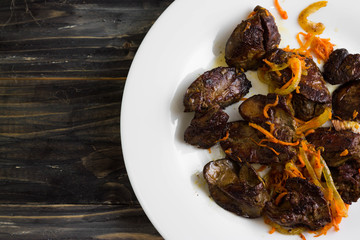 Fried chicken liver with vegetables on a white plate