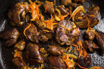 Fried chicken livers and hearts with vegetables in a frying pan