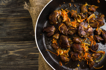 Fried chicken livers and hearts with vegetables in a frying pan