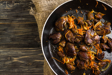 Fried chicken livers and hearts with vegetables in a frying pan
