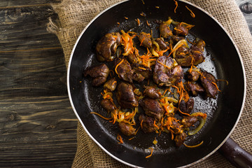 Fried chicken livers and hearts with vegetables in a frying pan