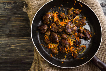 Fried chicken livers and hearts with vegetables in a frying pan