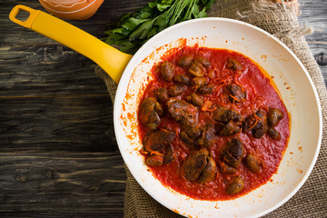 Fried chicken livers and hearts in tomato sauce in a frying pan