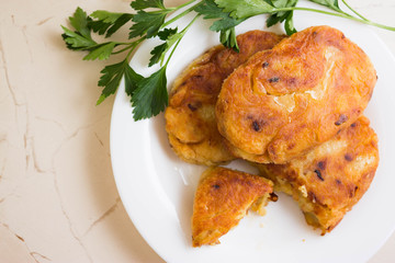 Potato patties with fried onions on a white plate