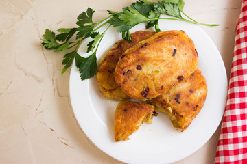 Potato patties with fried onions on a white plate