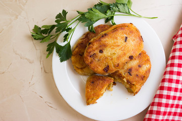 Potato patties with fried onions on a white plate