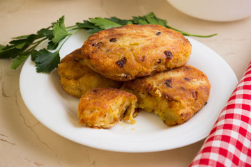 Potato patties with fried onions on a white plate