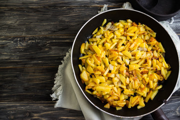 Fried potatoes in a frying pan on a wooden background in rustic style