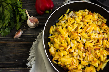 Fried potatoes in a frying pan on a wooden background in rustic style