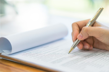 Hand with pen over application form .