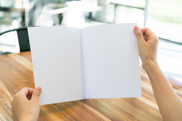 Obraz premium Women hand hold Bifold white template paper on wood texture .