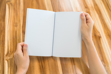 Hands open book on wood table .