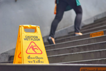 Yellow signs inside the hall, a warning sign Caution wet floor. Photo Challenge Thailand and written English.