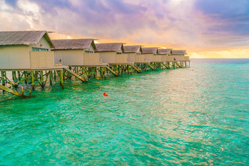 Fototapeta na wymiar Beautiful water villas in tropical Maldives island at the sunset