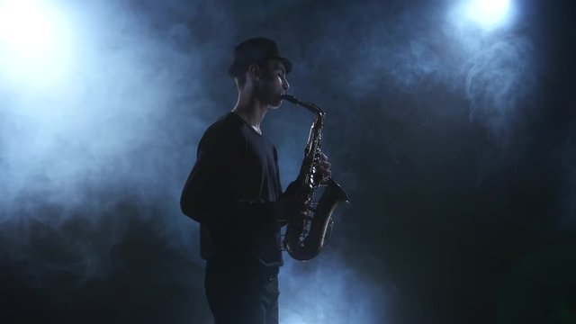 On dark smoky studio improvisation jazz music on saxophone