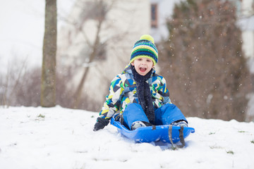 Fototapeta na wymiar Two kids, boy brothers, sliding with bob in the snow, wintertime