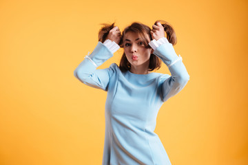 Charming amusing young woman making ponytails and funny face