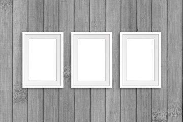 Three blank photo frames on old wooden panels wall. Interior decor background, gallery style mock up