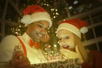 Fototapeta na wymiar Interracial couple opening an amazing gift on christmas eve